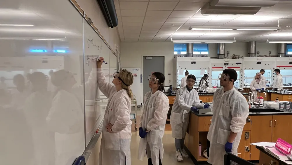 Students work on an equation in the chemistry lab