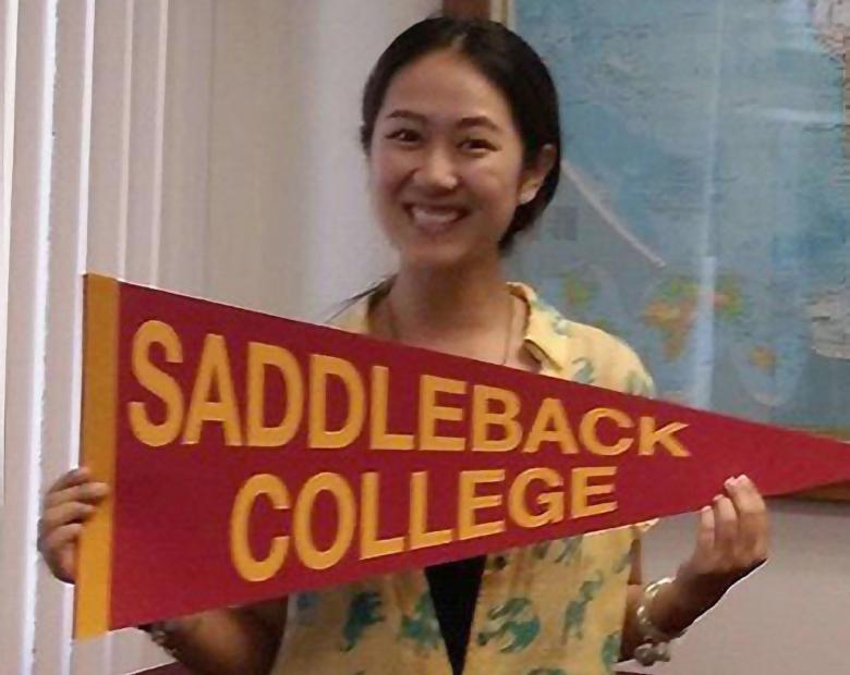 An International Student holding a Saddleback College pennant