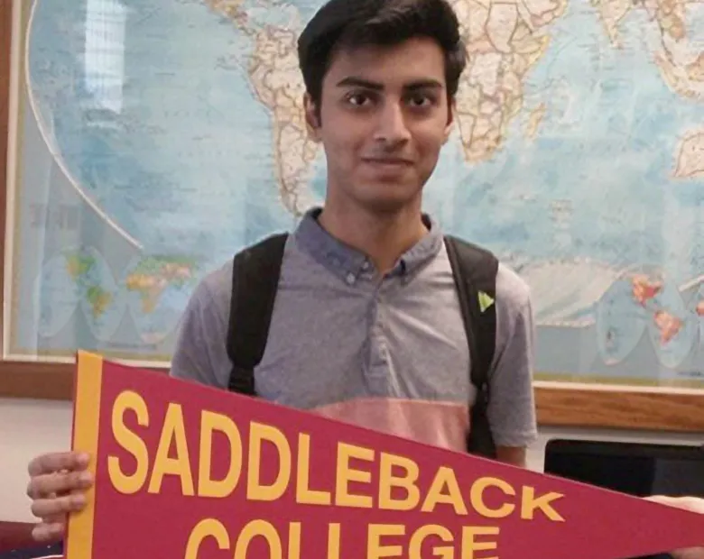 International student holding a Saddleback College pennant