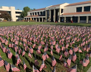 Small American flags arranged in the grass to make a larger flag display on the Saddleback College quad.