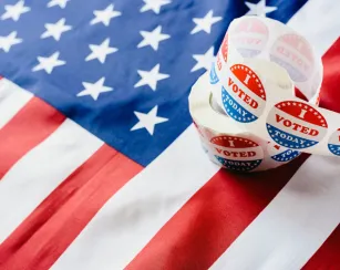 Image of a roll of I Voted Stickers resting on an American flag.