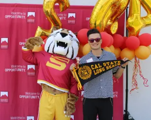Mascot and student holding CSULB pennent.