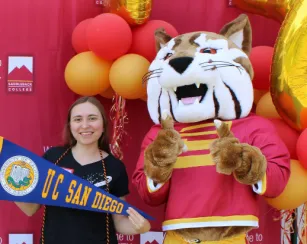 Female holding UCSD pennant with Saddleback Bobcat mascot