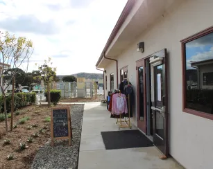 outside of care corner building on a cloudy day, clothes hanging on racks, greenery