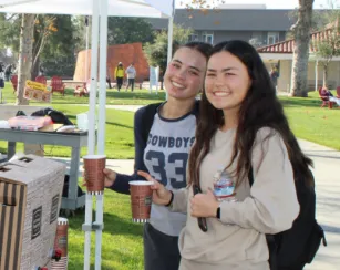 three female students drinking warm beverages from hot cups